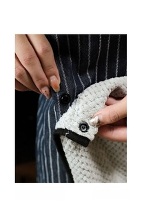 Detail of detachable absorbent towel layer with metal snap button on blue striped apron