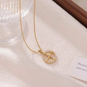 Collier boussole doré avec pendentif étoile et zircons sur fond de tissu blanc texturé