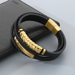 Close-up of multi-layer black leather bracelet with gold metal accents and magnetic clasp