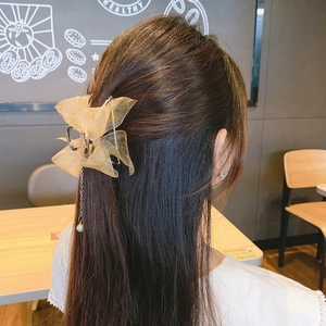 Detail of gauze bow hair claw clip with pearl tassel pendant on model hair