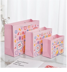 Drei pinke Cartoon-Geschenktüten aus Papier mit Hasenmotiven und Happy Birthday Schrift