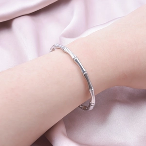 Minimalist silver bamboo design stainless steel open bangle worn by a female model