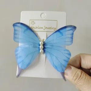 Detail showing a 10cm blue tulle butterfly hair clip with white pearl center beads
