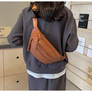 Detail of brown woven leather chest bag with adjustable orange strap on a model back
