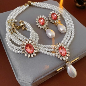 Détail de parure collier perles multicouches et boucles d'oreilles fleurs roses