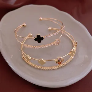 Golden double-layer open bangle with zircon clover charms on an elegant velvet cloth
