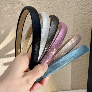 Close-up of glitter candy-colored headbands in six vibrant fabric shades held by hand