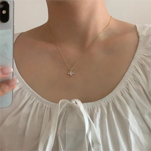 Close-up of a delicate gold cross necklace with sparkling stones on a person's neck