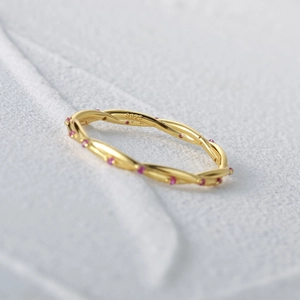 Macro view of braided S925 silver ring with gold plating and pink gemstones detail