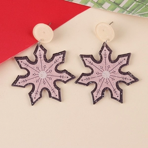 Macro detail of pink glitter snowflake earrings with black outline and elegant ear hooks
