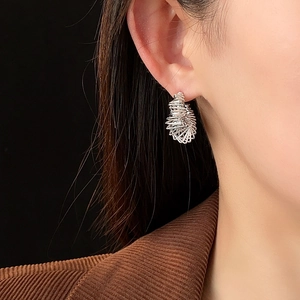 Macro shot of silver-plated twisted C-shaped earrings worn on model with metal shine