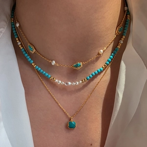 Detail of layered 18K gold necklace with freshwater pearls and turquoise stone beads