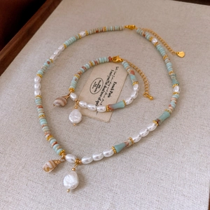 Close-up of freshwater pearl and blue stone necklace with shell pendant and jewelry set