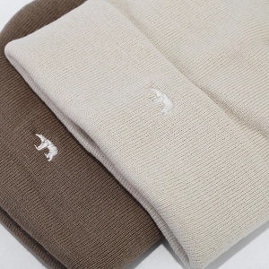 Detailed close-up of thick winter knit beanies with polar bear embroidery in two colors