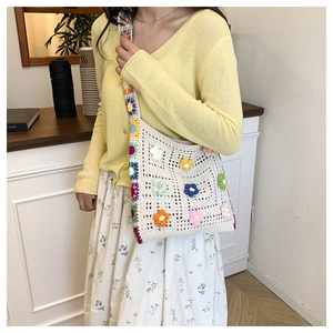 Detail of handmade crochet shoulder bag with colorful floral knit patterns and woven strap
