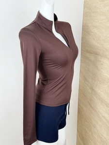 Detail of the high-stretch fabric and quarter-zip collar on this brown yoga top