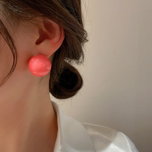 Close-up of pink spherical resin stud earring worn by model for a minimalist style