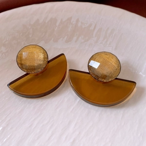 Close-up of vintage geometric resin drop earrings in amber with golden glitter accents