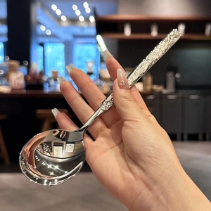 Close-up of a silver stainless steel soup spoon featuring an elegant embossed handle