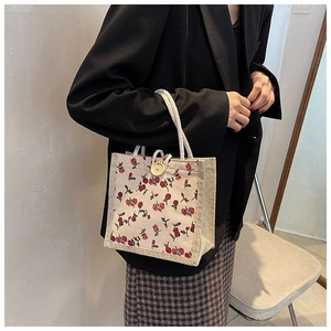 Close-up of floral linen handbag with white rope handle and wooden button detail