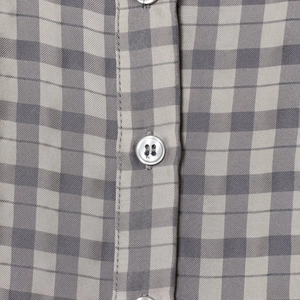 Short plaid dress in grey and white with close-up detail of a white button on fabric