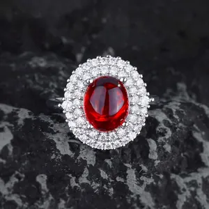 Macro shot of oval ruby ring with double halo pavé zircons on black volcanic rock