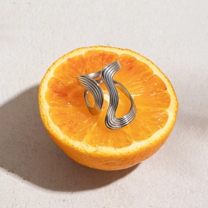 Artistic detail of a silver wavy stainless steel ring placed inside an orange slice