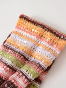Detailansicht von bunt gestreiftem Strickstoff mit schimmerndem Paillettenbesatz