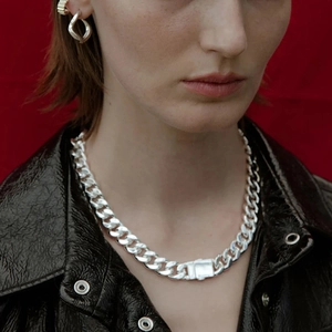Woman wearing bold stainless steel Cuban chain necklace and matching hoop earrings