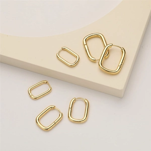 Three sizes of polished gold rectangular hoop earrings displayed on a beige pedestal