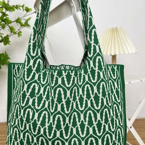 Detailed view of large knitted tote bag with green and white wave pattern in home setting