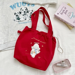 Top view of red canvas drawstring tote bag with cartoon embroidery and lifestyle props