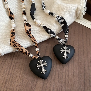 Detail of leopard print necklaces with heart cross pendants on a rustic wood background