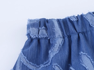 Detail view of denim jacquard fabric texture with elastic waistband and frayed tassel edges