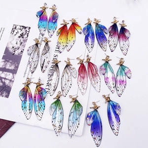 Detailed close-up of gradient cicada wing earrings with shimmering glitter and metal hooks