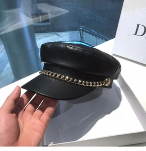 Detail of black faux leather baker boy hat with decorative gold chain accent