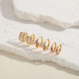 Three pairs of elegant gold huggie earrings with colorful cubic zirconia on stone pedestals