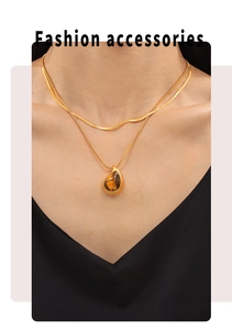 Close-up of double-layer gold necklace featuring a tiger eye teardrop pendant