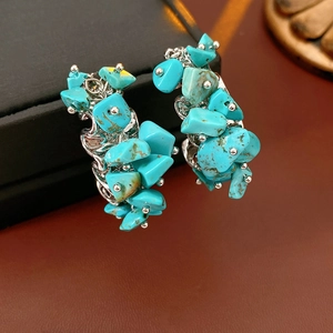 Détail macro de boucles d'oreilles C argentées avec pierres turquoise et texture organique