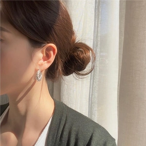 Close-up of S925 sterling silver rope twist hoop earrings worn by a model in soft light