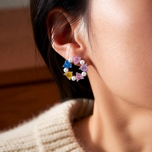 Close-up of elegant circular stud earrings with colorful heart gems and white pearls