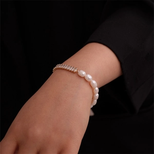 Detail of elegant gold chain bracelet with rectangle zircons and irregular white pearls
