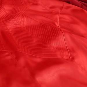 Macro detail of red satin evening gown fabric showing stitching and glossy texture