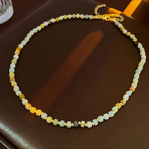 Detail view of colorful cylindrical beads and gold spacers on a minimalist beaded necklace