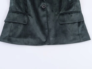 Détails d'un blazer en velours vert foncé avec poches à rabat et bouton central précis