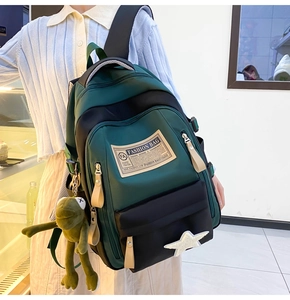 Side view of large green and black color-block backpack with frog plush and star patch