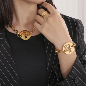 Detail of chunky gold chain necklace and bracelet set with Tree of Life round pendants