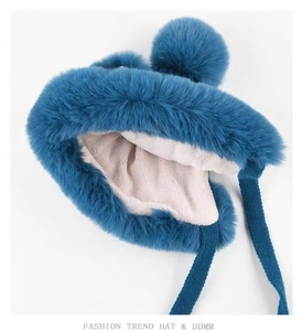Detail showing plush peacock blue earflap hat with thick faux fur and beige fleece lining