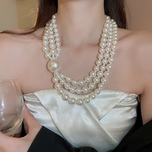 Elegant triple-layer pearl necklace with a large focal pearl shown on a model