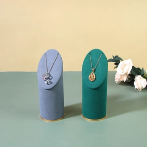 Luxury velvet jewelry stand with gold metal base displaying silver and gold necklaces